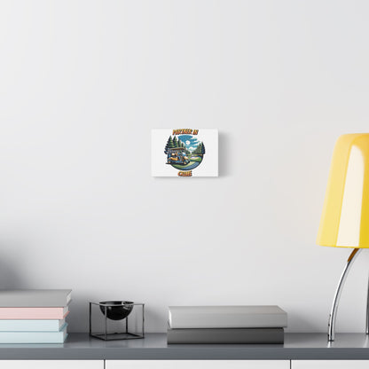 Small canvas wall art hanging on a modern white wall above a minimalist grey desk with stacked books, a black candle holder, and a yellow desk lamp. The artwork shows a golf scene with a cart and trees and the words 'PARTNER IN CRIME' in bold letters above and below the image.